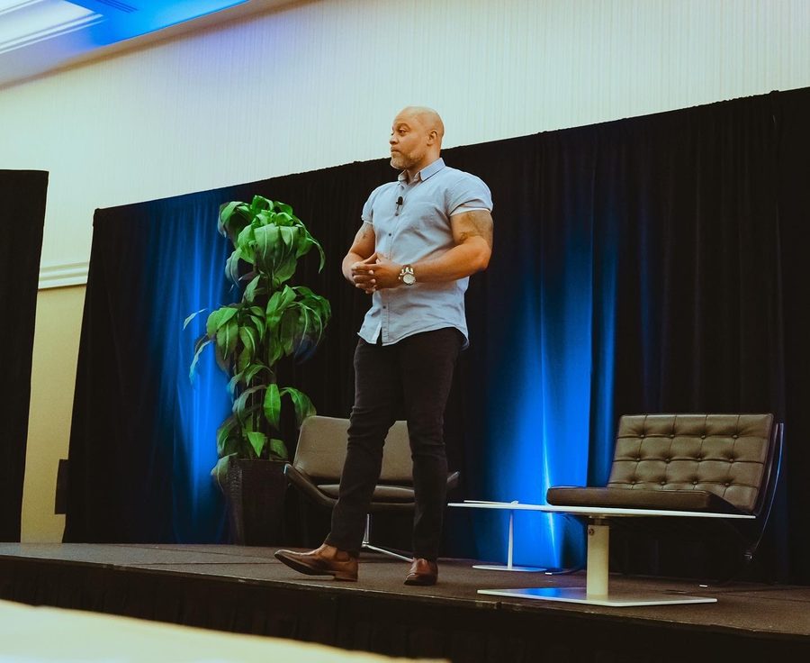 Princeton Clark speaking on stage with dramatic lighting